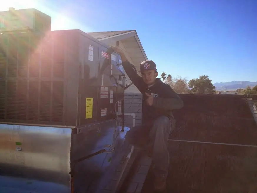 HVAC technician performing AC Tune-Up on a rooftop unit in Fort Wayne